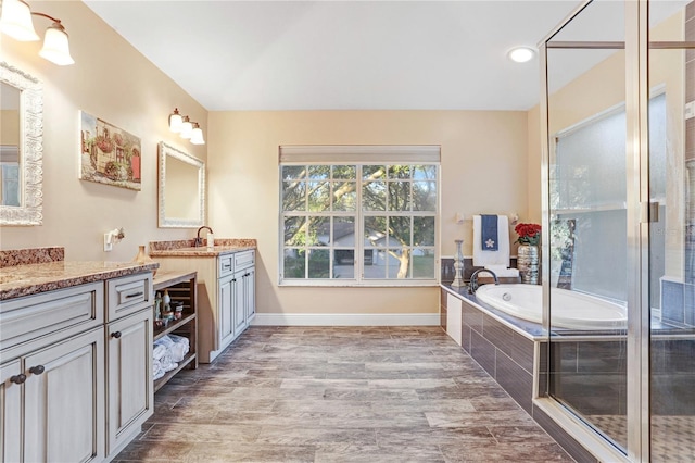 full bath with a garden tub, vanity, baseboards, and wood finished floors