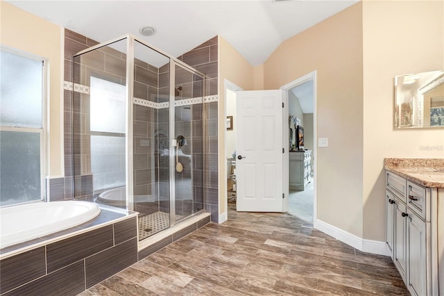 bathroom with a stall shower, a garden tub, vanity, and wood finished floors