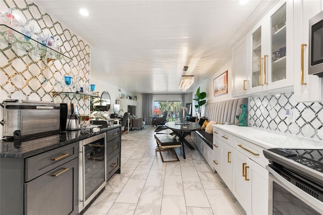 kitchen with beverage cooler, glass insert cabinets, marble finish floor, stainless steel appliances, and white cabinetry