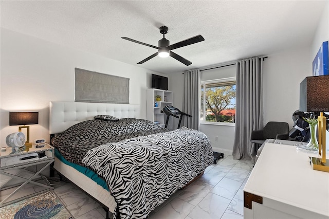 bedroom featuring a ceiling fan, marble finish floor, a textured ceiling, and baseboards