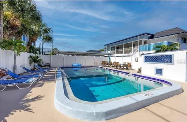 pool with a sunroom, a patio area, and fence