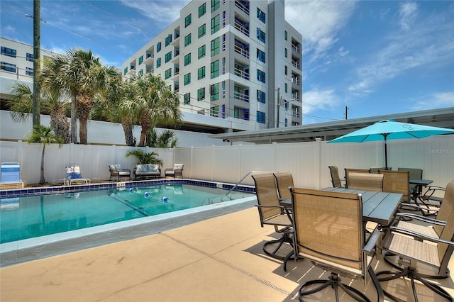 pool featuring a patio area, fence, and outdoor dining area