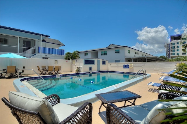 pool with a patio, fence, and a sunroom