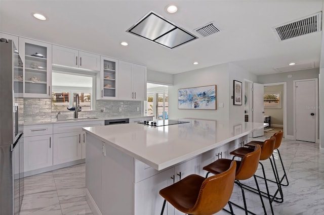 kitchen featuring visible vents, freestanding refrigerator, a sink, black electric cooktop, and marble finish floor