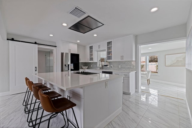 kitchen with visible vents, stainless steel refrigerator with ice dispenser, tasteful backsplash, a kitchen island, and a barn door