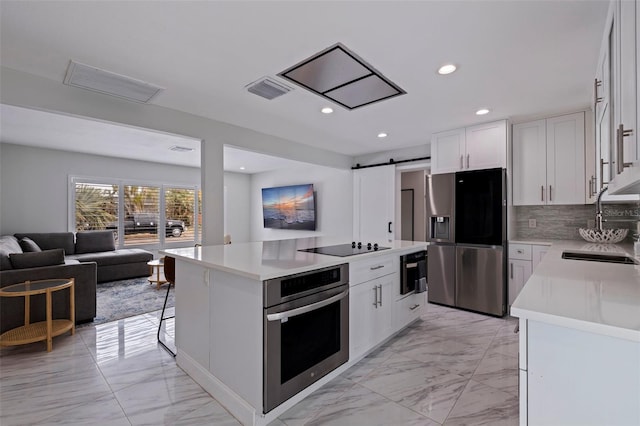 kitchen with a sink, stainless steel appliances, a barn door, and marble finish floor