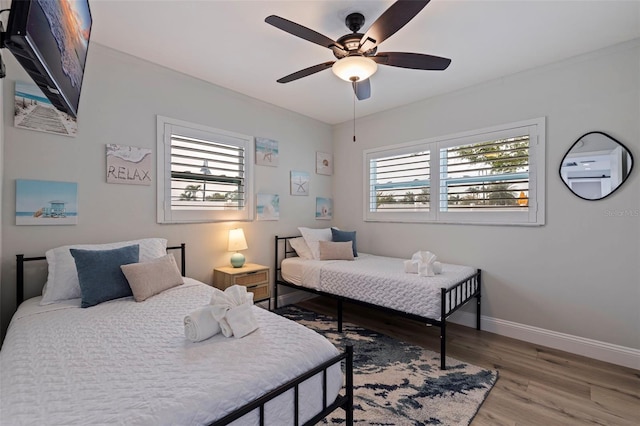 bedroom with a ceiling fan, wood finished floors, and baseboards