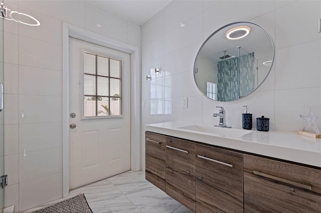 full bathroom featuring marble finish floor, tile walls, vanity, and a tile shower