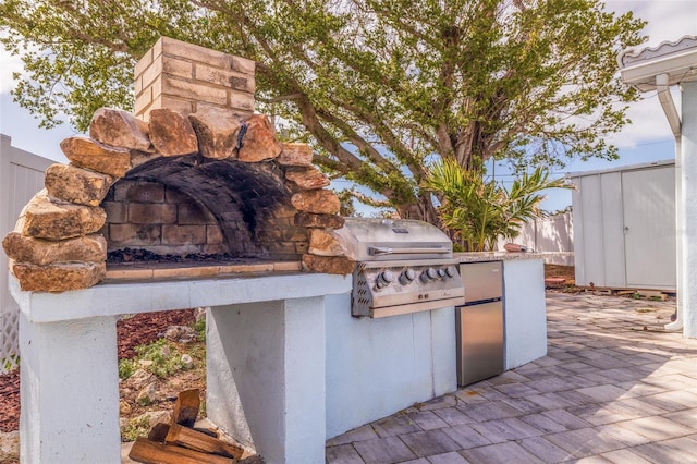 view of patio with area for grilling, an outdoor structure, and fence