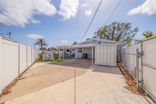 rear view of property featuring a patio, a fenced backyard, concrete driveway, a carport, and central AC unit