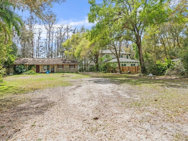 view of front facade featuring dirt driveway and fence