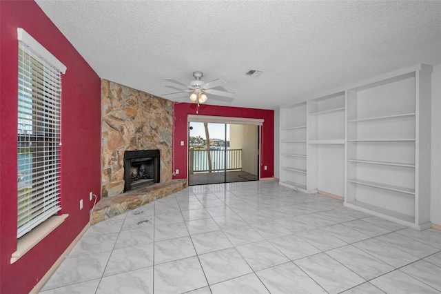 unfurnished living room featuring a textured ceiling, ceiling fan, a fireplace, visible vents, and built in features