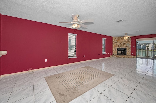 unfurnished living room with baseboards, visible vents, ceiling fan, a textured ceiling, and a fireplace