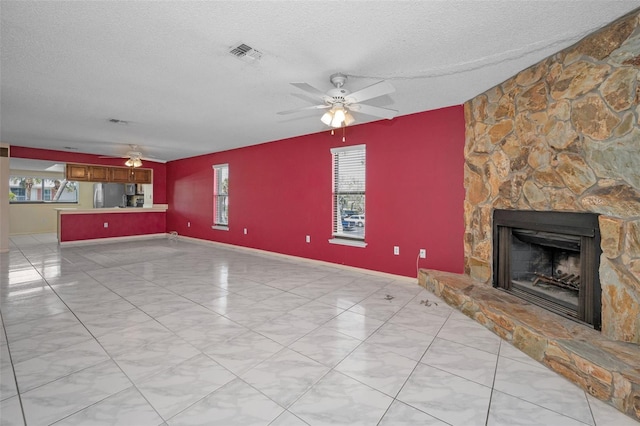 unfurnished living room featuring a textured ceiling, a fireplace, visible vents, and a ceiling fan