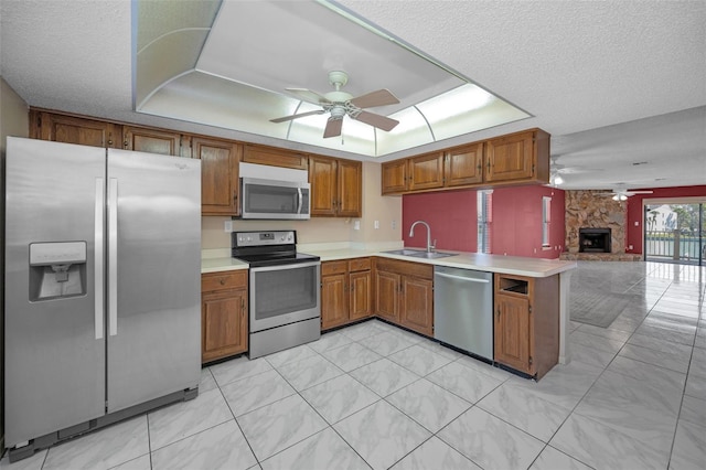 kitchen featuring brown cabinets, open floor plan, a peninsula, stainless steel appliances, and a sink