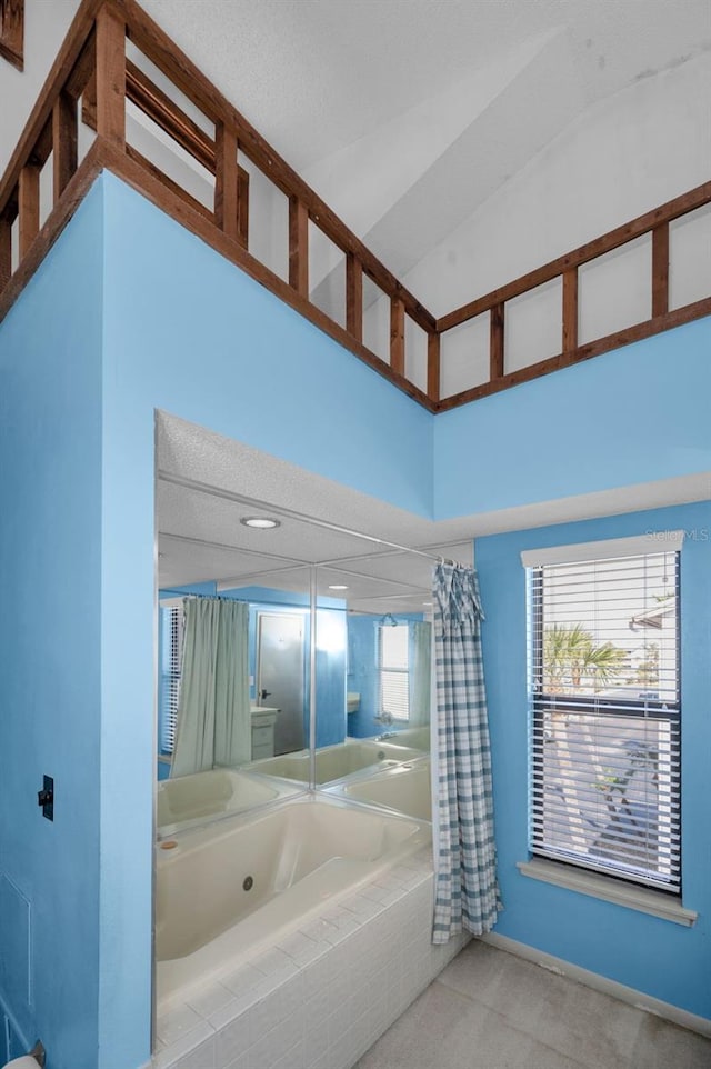 bathroom featuring tiled bath, baseboards, a towering ceiling, and a shower with shower curtain