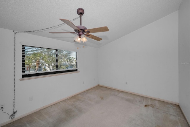 empty room with light carpet, ceiling fan, a textured ceiling, and baseboards