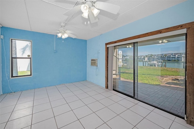 tiled empty room with a water view, a ceiling fan, and an AC wall unit