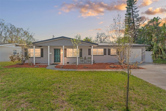 ranch-style home featuring driveway, a garage, a lawn, and stucco siding