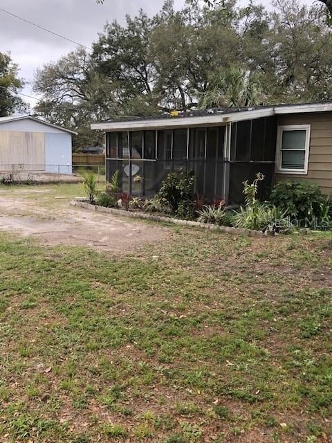 back of house featuring a lawn and a sunroom