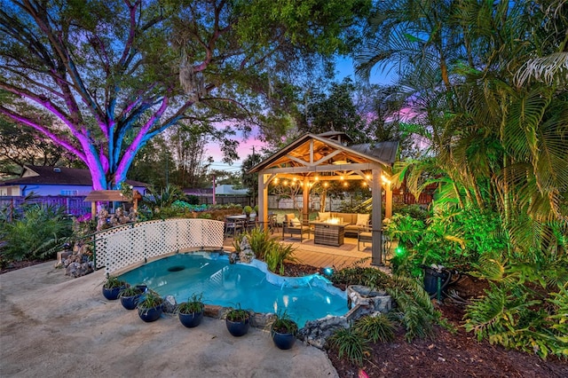 pool at dusk featuring a patio, fence, a gazebo, and an outdoor hangout area