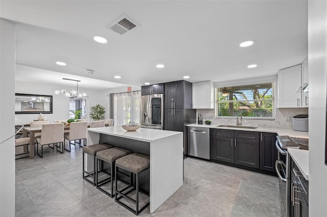 kitchen featuring a breakfast bar, light countertops, visible vents, appliances with stainless steel finishes, and a sink