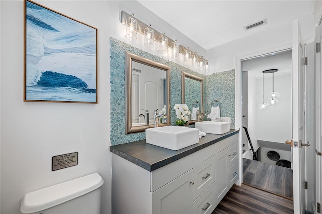 full bathroom with toilet, visible vents, a sink, and wood finished floors