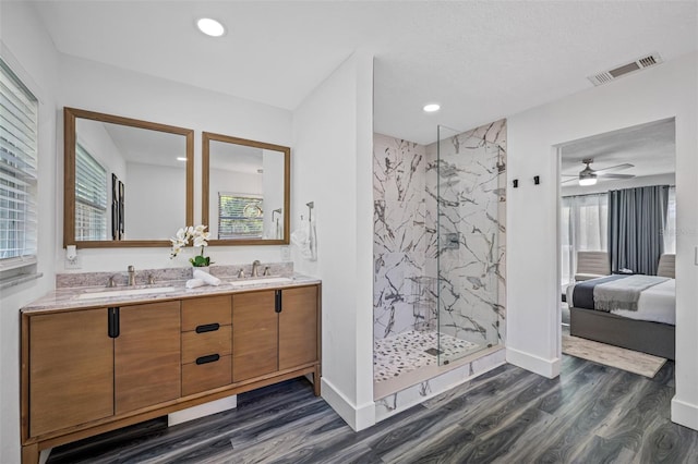 bathroom featuring a marble finish shower, visible vents, a sink, and wood finished floors