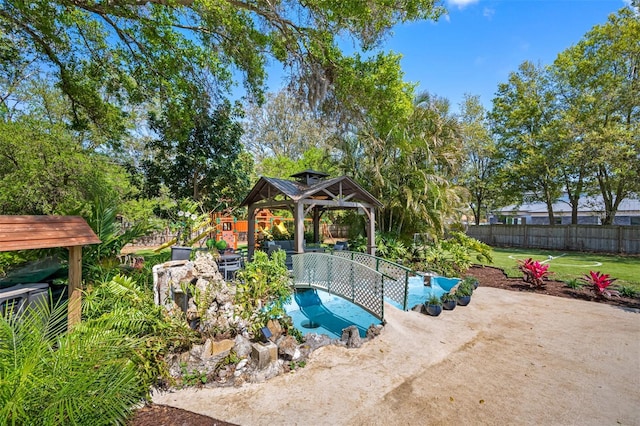 view of swimming pool with a yard, fence, and a gazebo