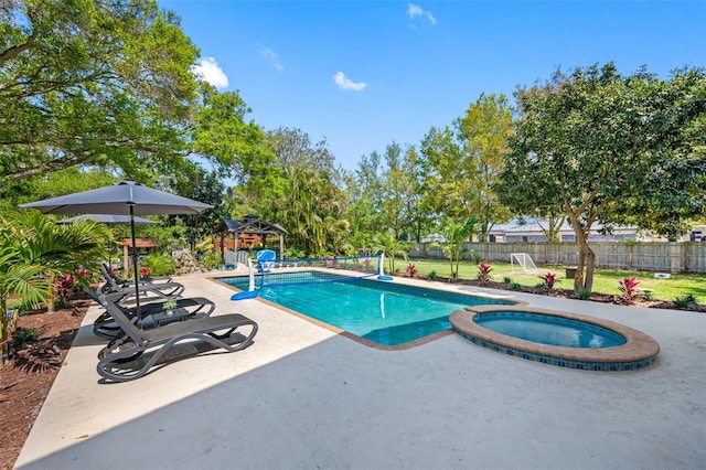 view of swimming pool featuring a pool with connected hot tub, a patio, a lawn, and fence