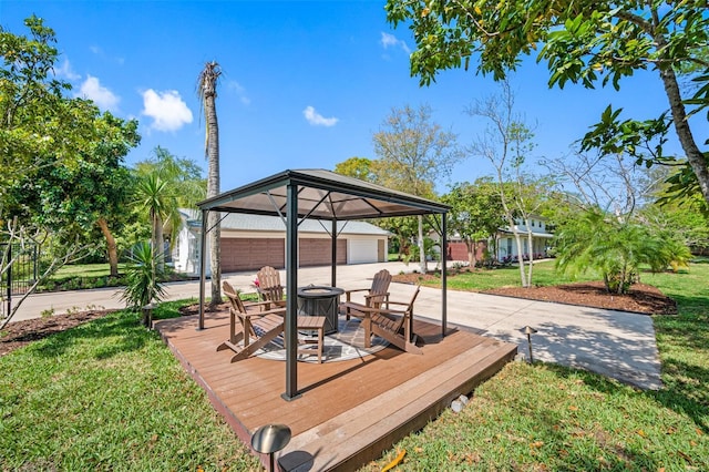 wooden deck with a garage, a yard, a fire pit, and an outdoor structure