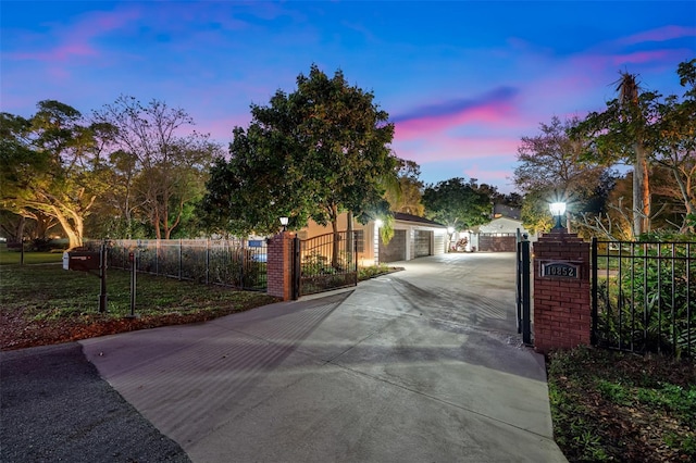 view of road with street lights, concrete driveway, a gated entry, and a gate