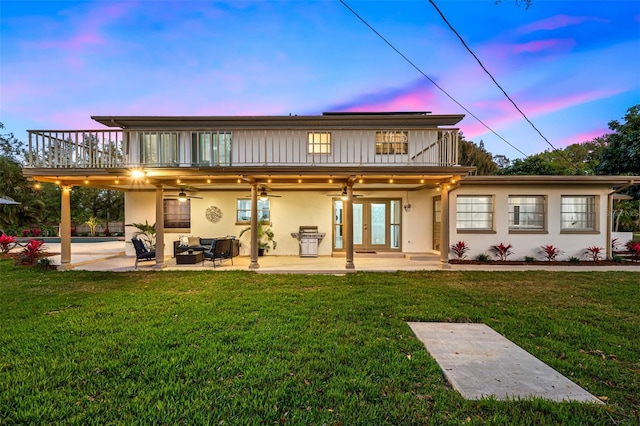 back of house featuring french doors, a yard, a balcony, and an outdoor hangout area