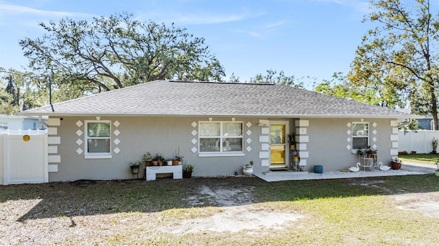 view of front of house with a shingled roof, a front lawn, fence, and stucco siding