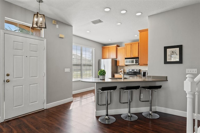 kitchen with dark wood finished floors, visible vents, decorative backsplash, appliances with stainless steel finishes, and a peninsula