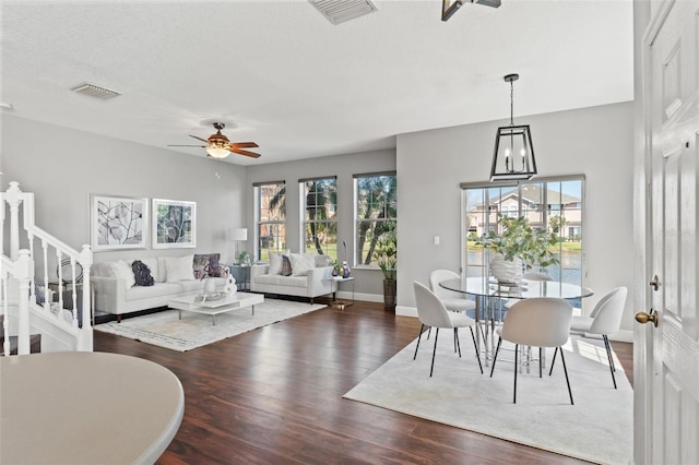 living room featuring stairway, ceiling fan, visible vents, and wood finished floors