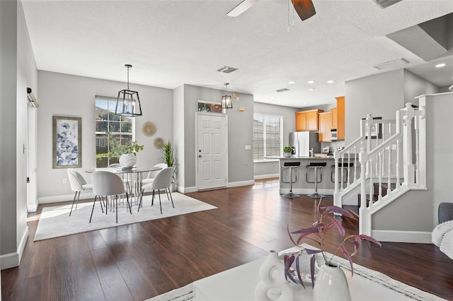 living room with dark wood-style floors, visible vents, and baseboards