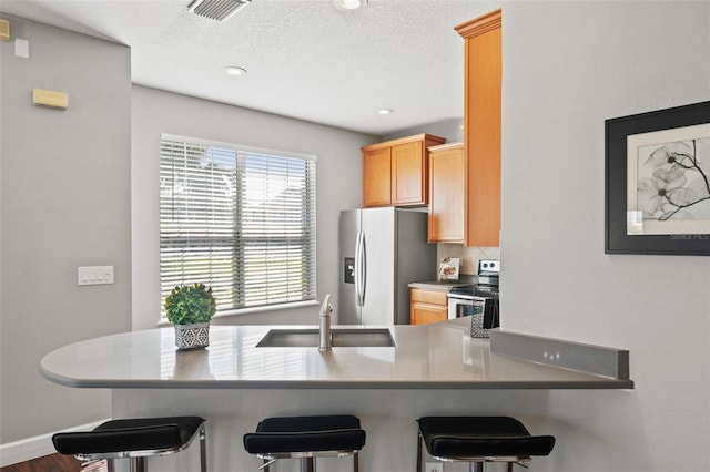 kitchen with stainless steel appliances, a breakfast bar, a sink, and visible vents