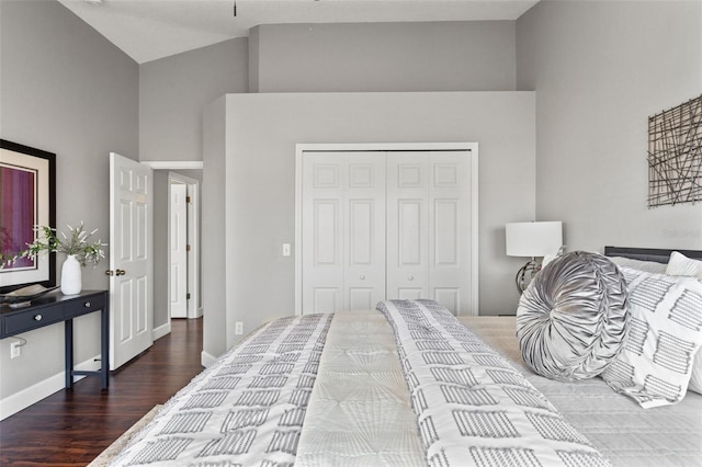 bedroom featuring a high ceiling, baseboards, a closet, and wood finished floors