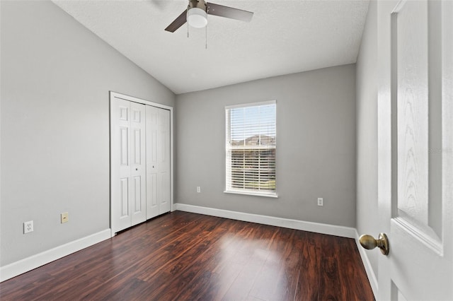 unfurnished bedroom featuring lofted ceiling, dark wood-style flooring, and baseboards