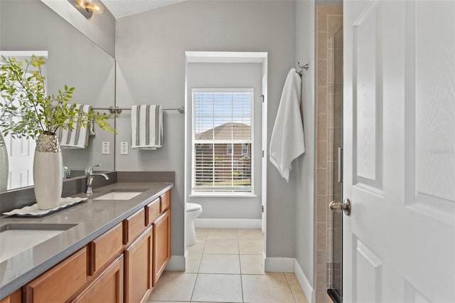 bathroom featuring toilet, a sink, a tile shower, tile patterned floors, and double vanity