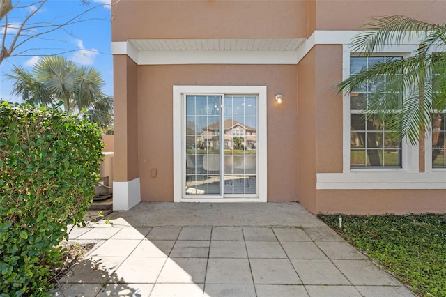 view of exterior entry featuring a patio and stucco siding