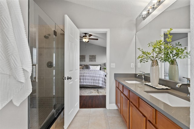 ensuite bathroom with lofted ceiling, connected bathroom, a sink, and tile patterned floors