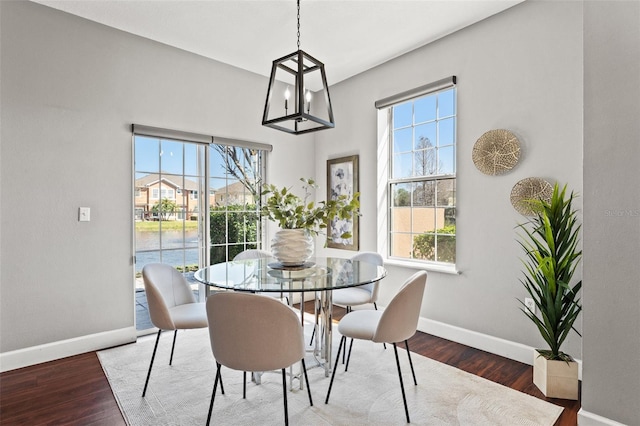 dining room with baseboards, a chandelier, wood finished floors, and a healthy amount of sunlight