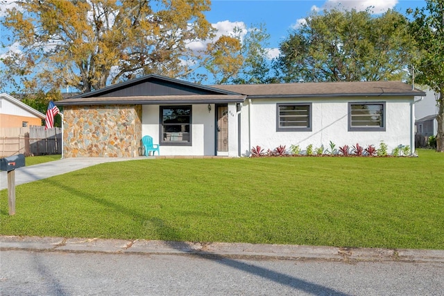 ranch-style home with a front yard, fence, driveway, and stucco siding