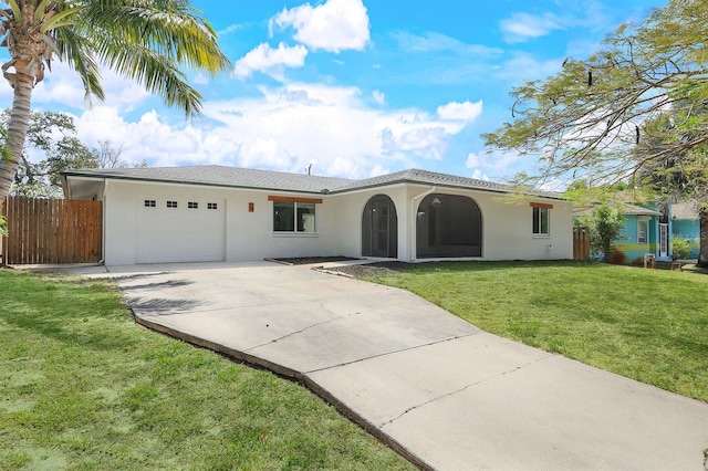 view of front of house with concrete driveway, an attached garage, fence, a front lawn, and stucco siding