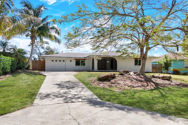 ranch-style home with a garage, fence, concrete driveway, stucco siding, and a front lawn