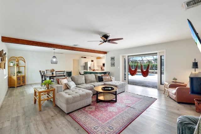 living area with visible vents, beamed ceiling, light wood-style flooring, and ceiling fan