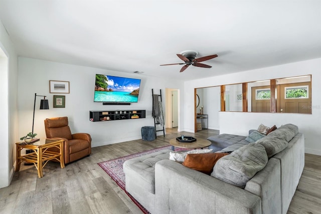 living area with light wood-style floors, visible vents, ceiling fan, and baseboards