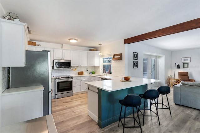 kitchen with a peninsula, a sink, open floor plan, appliances with stainless steel finishes, and decorative backsplash